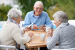 © Alexandra W/peopleimages.com - Poker, smile and senior group with retirement, outdoor and cheerful together with joy, relax and playful. Elderly people, old man and mature women outside, card games and chilling with social bonding