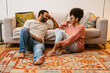 © Drobot Dean - Cheerful couple talking while sitting on floor at home