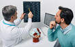 © Peakstock - Man with migraine and headache at consultation with neurologist who looking at MRA of patient's head to analyze his brain health. Cerebrovascular MRI