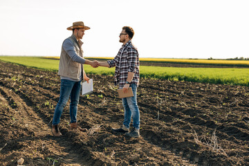 two men shake hands on the field. buying property.