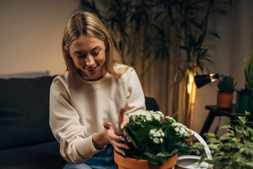 Wall Mural - A cute blond woman is potting a plant with white flowers.