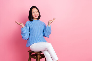 Photo of positive lovely person sit chair raise hands communicate say tell empty space isolated on pink color background