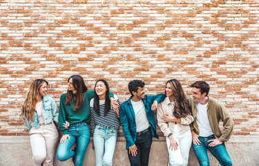 Group of young people having fun outdoors - Happy friends embracing over colorful brick wall - Friendship concept with guys and girls hanging out on summer vacation