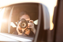 Golden Sunlit Reflection Of Photographer On Road Trip In Car Passenger Mirror