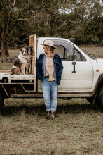 Woman Leans Against Ute In A Paddock.