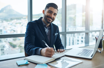 Aufkleber - Business is looking good. Portrait of a young businessman writing in a notebook at his desk in a modern office.