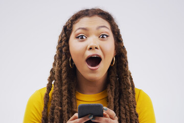 Poster - The wireless world is filled with surprised. Studio shot of a young woman looking surprised while reading something on her cellphone.