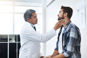 Wall Mural - Look up for me. a mature male doctor doing a check up on a young patient whos seated on a doctors bed.