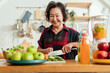 © whyframeshot - healthy asian aunt retired female woman enjoy making cook clean food breakfast for her healthy food lifestyle,smiling cheerful woman chopping fresh vegetable fruit making smoothie drink at home