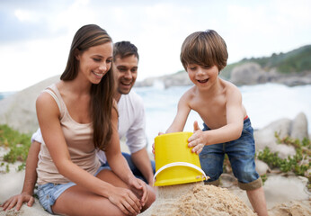 Sticker - Family, child and sand castle at beach in summer for fun, travel or holiday with a smile. A man, woman and excited kid playing together on vacation at sea with a toy bucket, development and happiness