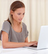 © Mark Freebs/peopleimages.com - Catching up on a few emails. A young woman sitting inside and working on her laptop.