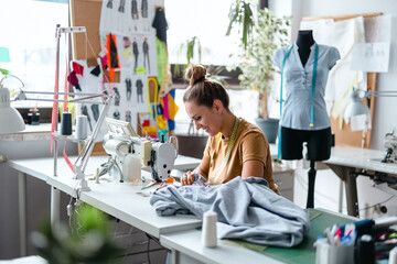 Wall Mural - Fashion designer using a sewing machine at her workplace
