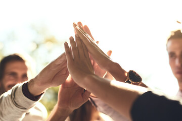 Poster - We rise when we lift each other up. a group of colleagues joining hands in solidarity outdoors.