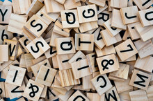 Background From Wooden Letters Of The Alphabet Randomly Scattered. Top View Of A Square Wooden Tile With The English Alphabet. The Concept Of The Development Of Thinking, Grammar.
