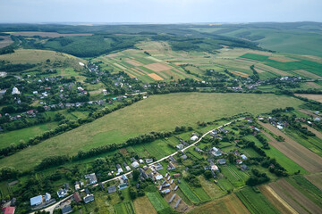 Wall Mural - Aerial landscape view of green cultivated agricultural fields with growing crops and distant village houses