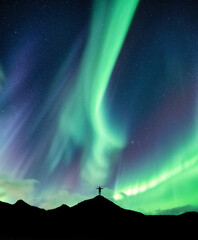 Wall Mural - aurora borealis glowing over silhouette hiker standing on the mountain in the night sky