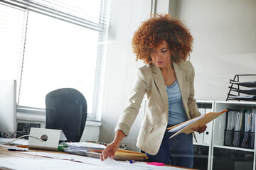 Aufkleber - Filing everything in the correct folder. a beautiful young businesswoman looking over some documents in her office.
