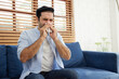 © offsuperphoto - young man having a cold, using tissue paper and blowing his nose on sofa