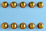 Fototapeta Tulipany - Gold coffee pods in a row against a plain background. Top down view.