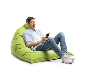 Wall Mural - Young man seated on a bean bag laughing and looking at a smartphone