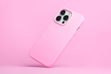 Wall Mural - iPhone 14 pro max and 13 in pink soft silicone case falls down back view, phone case mockup in monochrome colours isolated on pink background