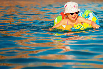 Wall Mural - Funny portrait of cute happy child girl swimming in the sea. Kid having fun outdoors with water. Summer vacation and healthy lifestyle concept. Horizontal image. Copy space.