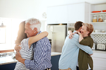 Wall Mural - You can never have too many hugs. a loving family greeting each other with hugs in the kitchen at home.