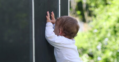 Wall Mural - Baby standing outside leaning on pool fence