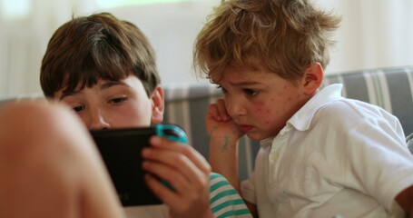 Canvas Print - Brothers at home holding tablet device watching content