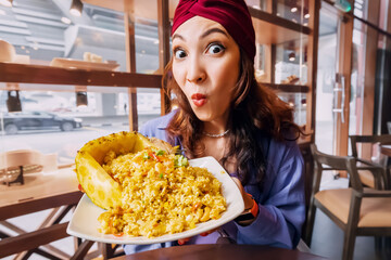 Happy girl with Thai rice and pineapple dish, that is a symphony of sweet and savory flavors that dance across your tongue. The juicy, tangy pineapple perfectly complements the fragrant jasmine rice