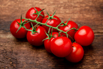 Poster - Branch of fresh cherry tomatoes on a brown wooden background.