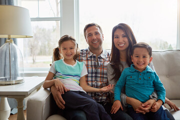 Family happens when two people fall in love. a happy young family of four relaxing together on the sofa at home.