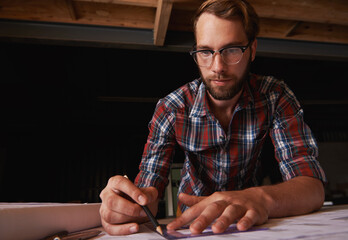 Canvas Print - All we need is art. a young man sitting indoors working on building plans.