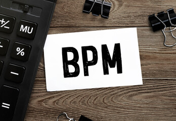 Poster - white paper with text bpm on a wooden surface with stationery