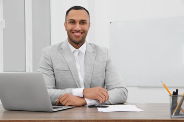 Canvas Print - Happy young intern working at table in modern office