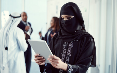 Poster - Working efficiently to get the job done. an attractive young arabic businesswoman working on a tablet in the office with her colleagues in the background.