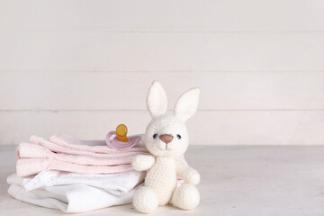 Wall Mural - Stack of baby clothes, toy bunny and pacifier on light table