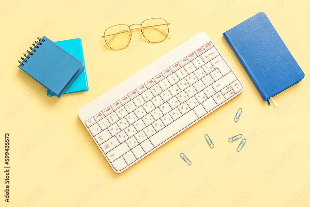 Composition with keyboard, glasses and notebooks on beige background