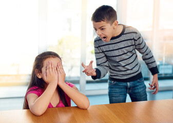 Wall Mural - They drive each other crazy. a little girl covering her face while her brother angrily screams at her at home.