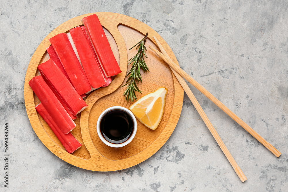Plate with tasty crab sticks and sauce on grunge background