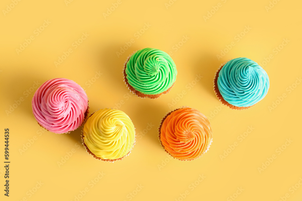 Tasty colorful cupcakes on yellow background