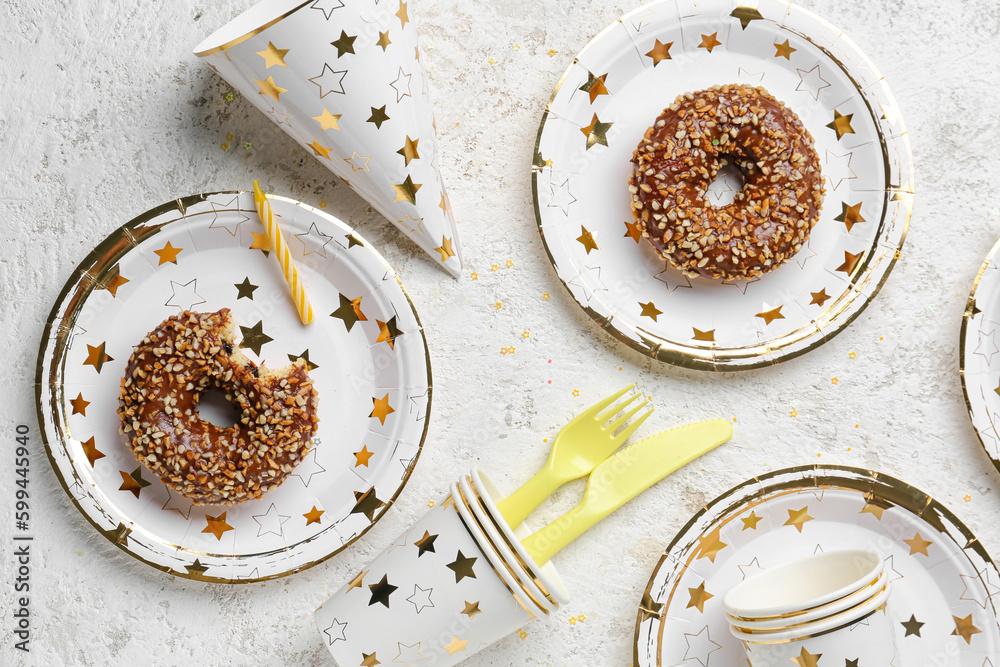 Paper disposable tableware with donuts and party hat on grunge background