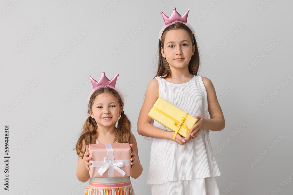 Little girls with gifts on light background. Children's Day celebration