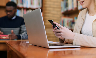 Poster - Maybe organizing a study group would help me. a university student using her cellphone while sitting behind a laptop.