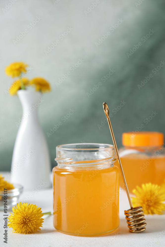 Jars with dandelion honey on white table