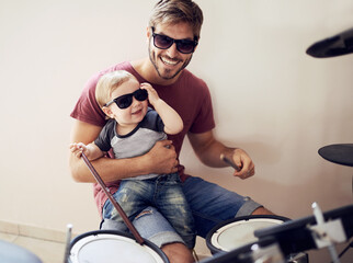 Poster - Feel the beat. A handsome young father teaching his young son to drum.