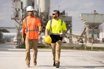 Industrial workers outdoors. Engineers in safety uniform and helmet on factory outdoor. Industrial engineers with factory worker. Factory industrial engineers walking outdoor.