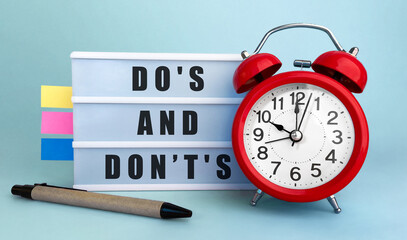 Poster - text dos and donts written on the lightbox with alarm clock and colorfull stickers on blue backgroun