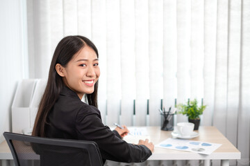 Beautiful young asia businesswoman is sitting at workplace and feeling ready for work all time.