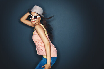 Sticker - Living on the fun side of life. Studio shot of an attractive and fun loving young woman posing against a dark background.